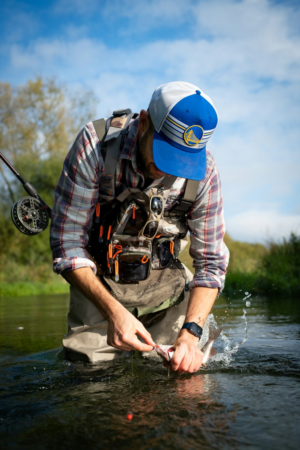 a man standing in a river holding a fish