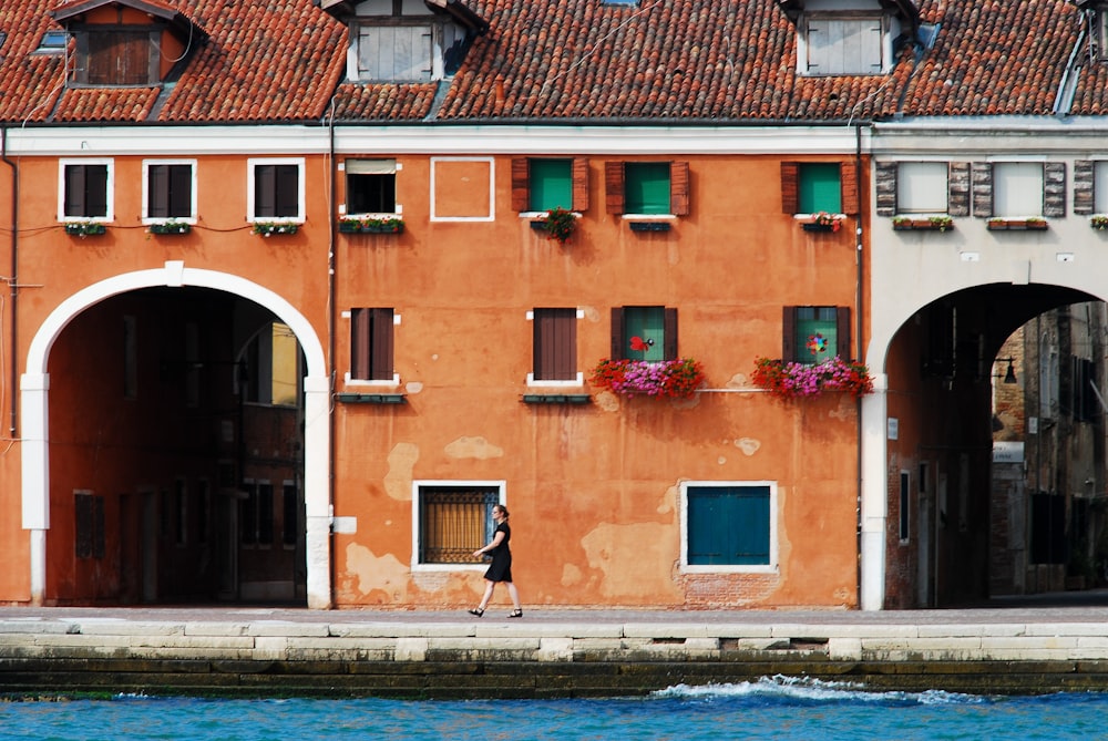 a woman walking down a street next to a building