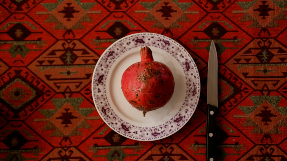 a pomegranate on a plate next to a knife