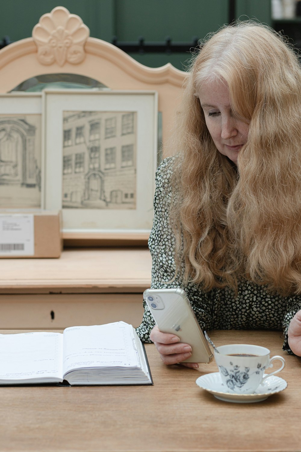 a woman sitting at a table with a book and a cup of coffee