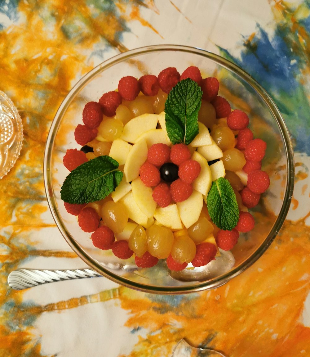 a glass bowl filled with fruit on top of a table