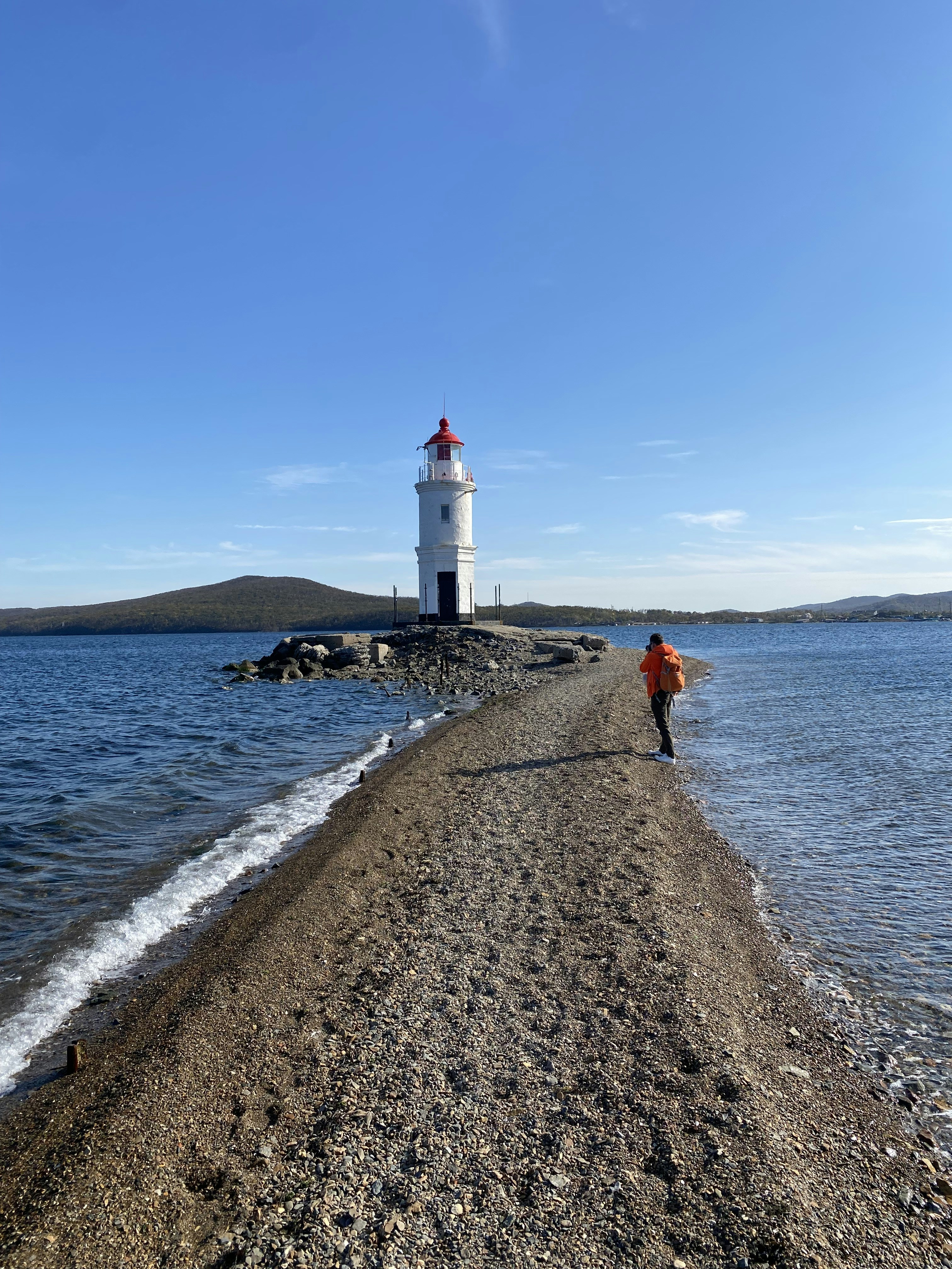 a person walking on a beach next to a light house