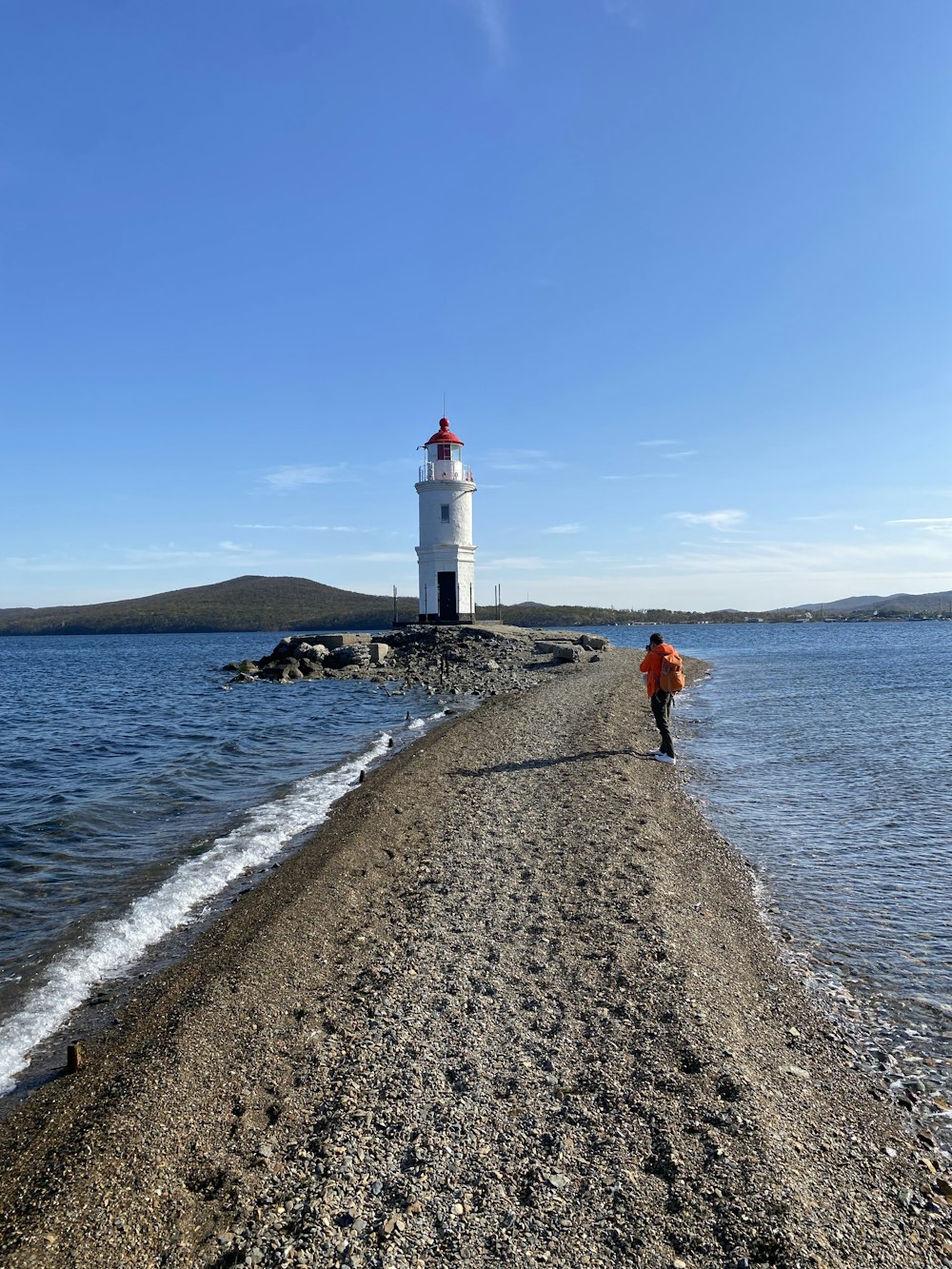 a person walking on a beach next to a light house