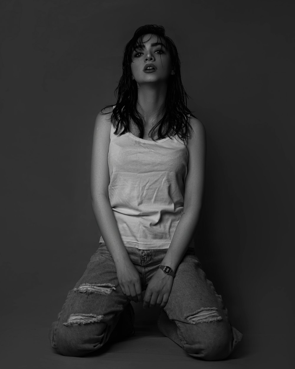 a black and white photo of a woman sitting on the floor