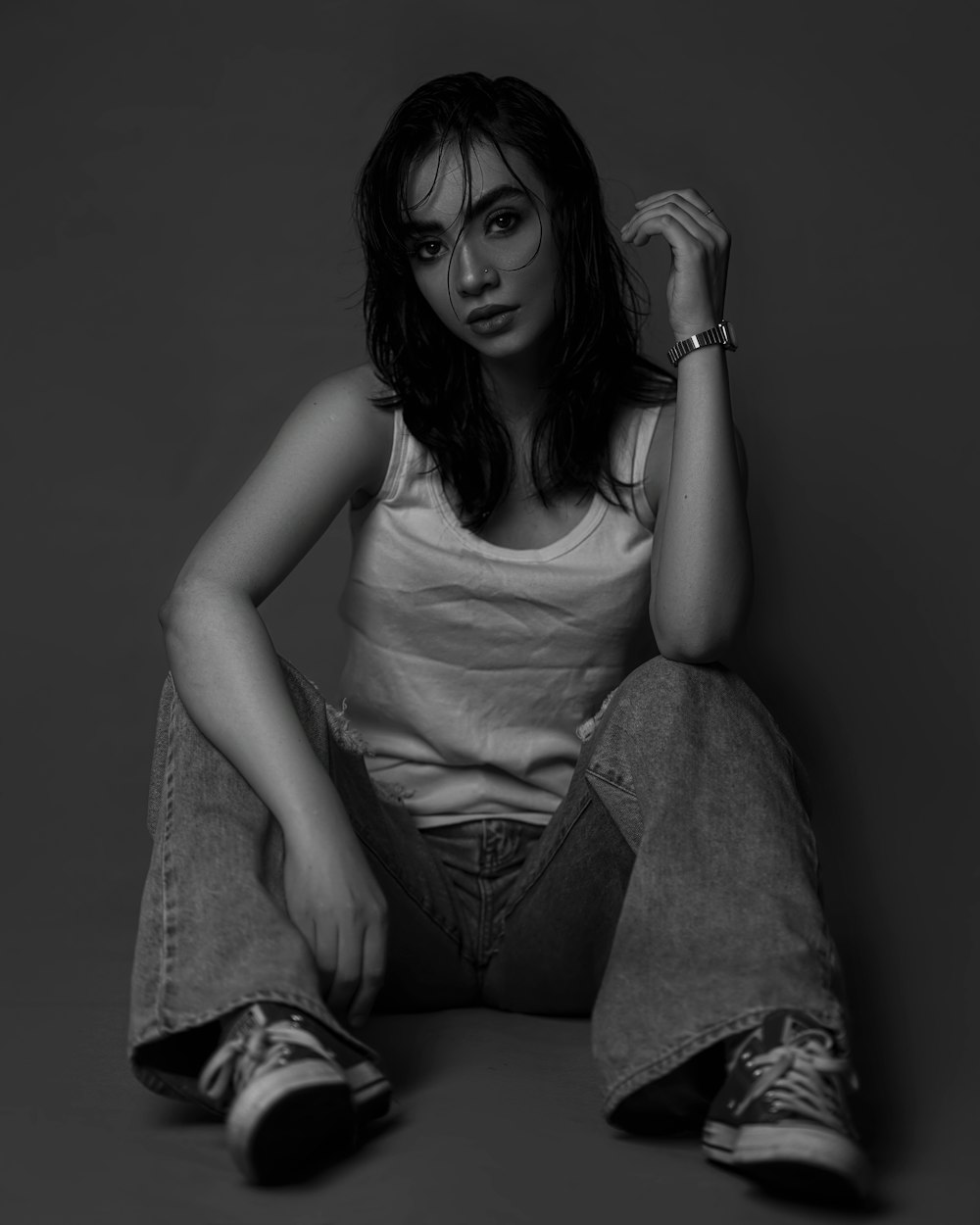 a black and white photo of a woman sitting on the floor