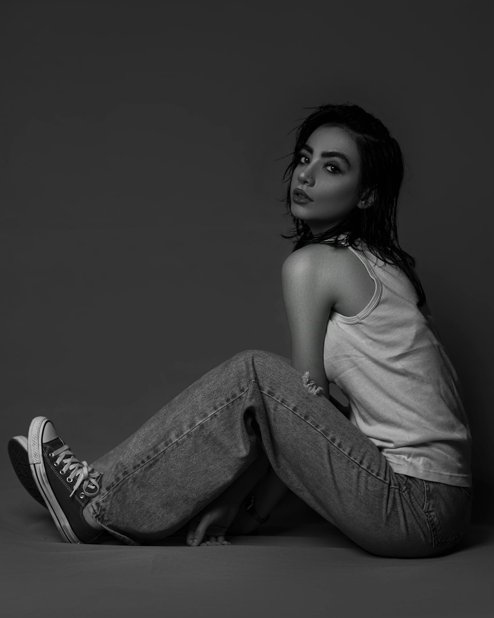 a black and white photo of a woman sitting on the floor