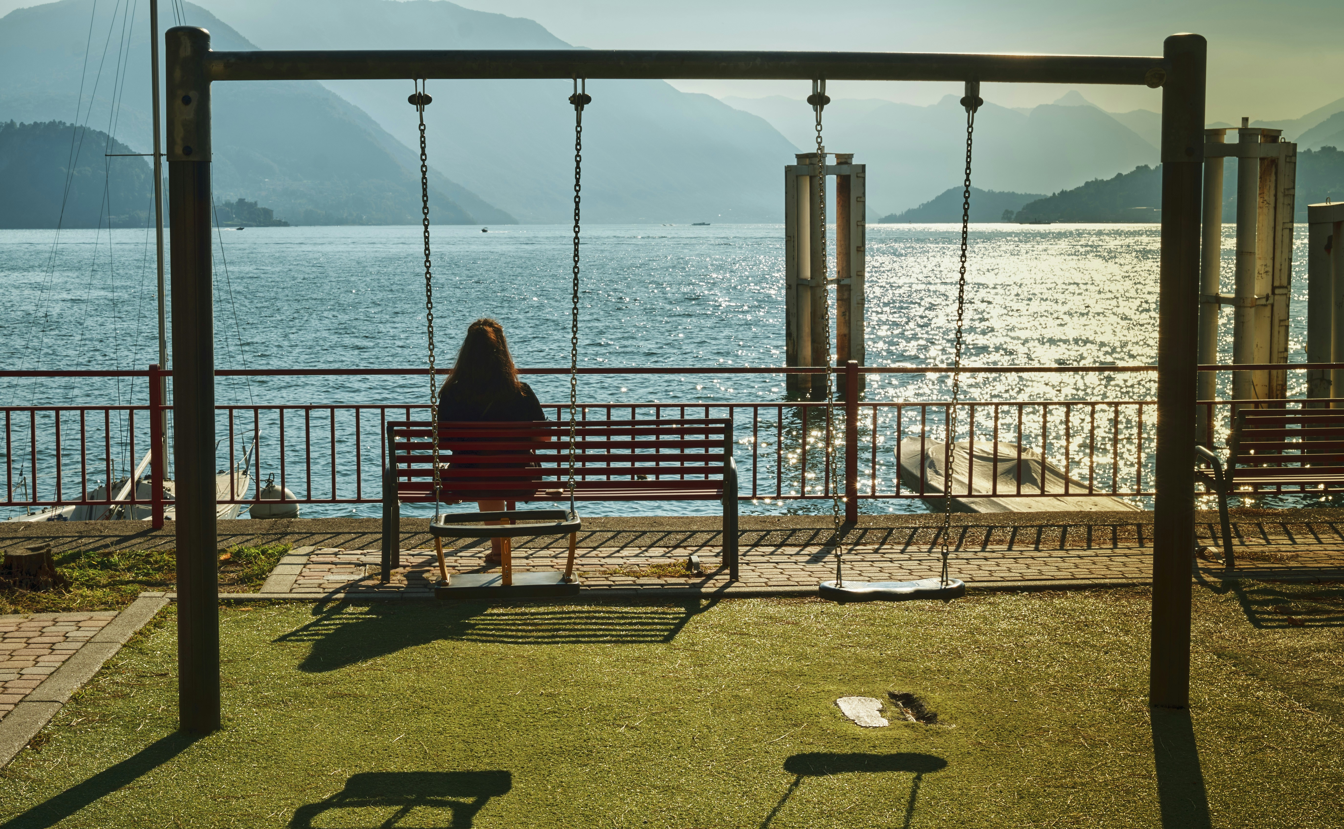 uma mulher sentada em um banco ao lado de um corpo de água