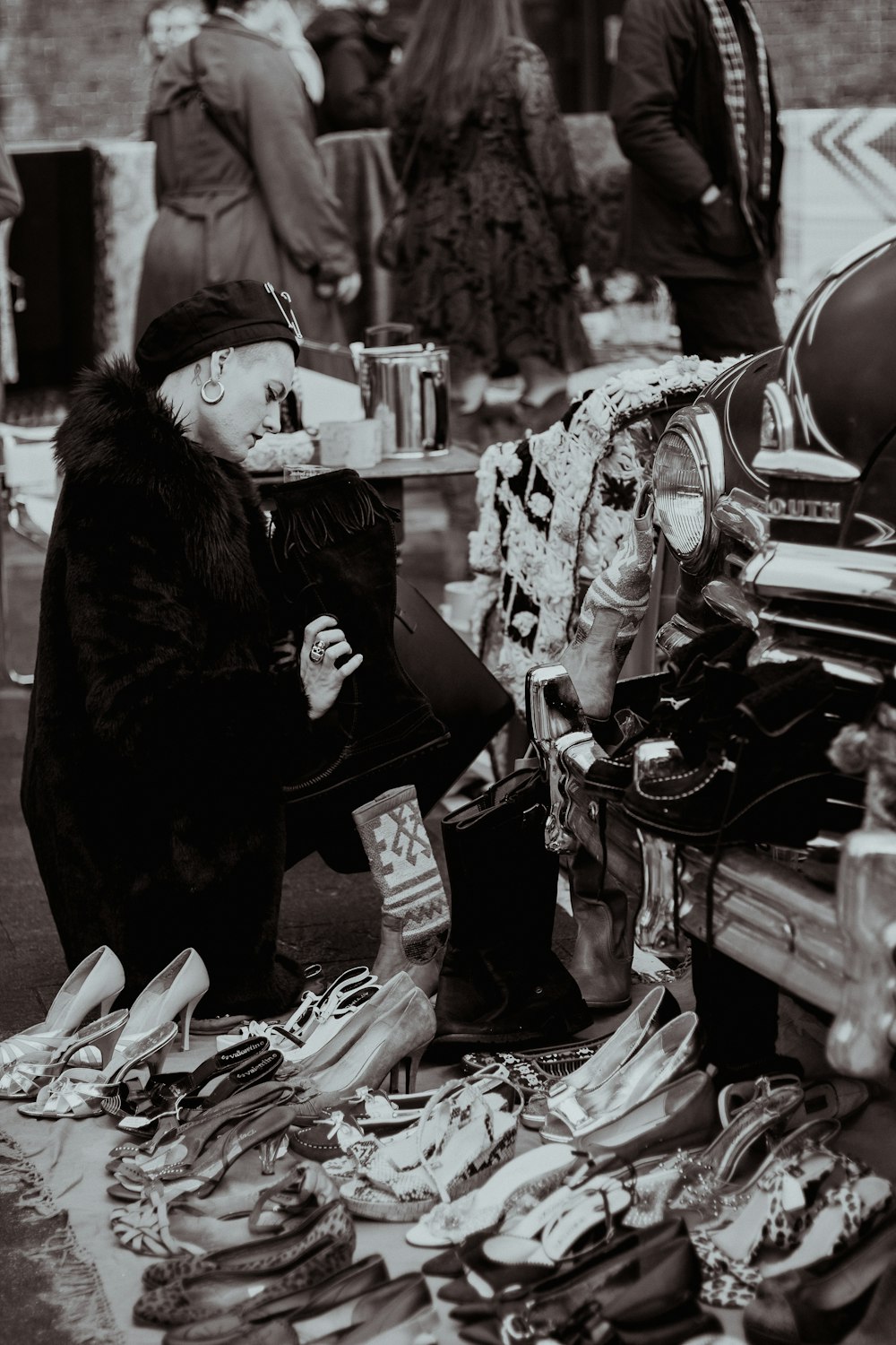 a man sitting on the ground next to a pile of shoes