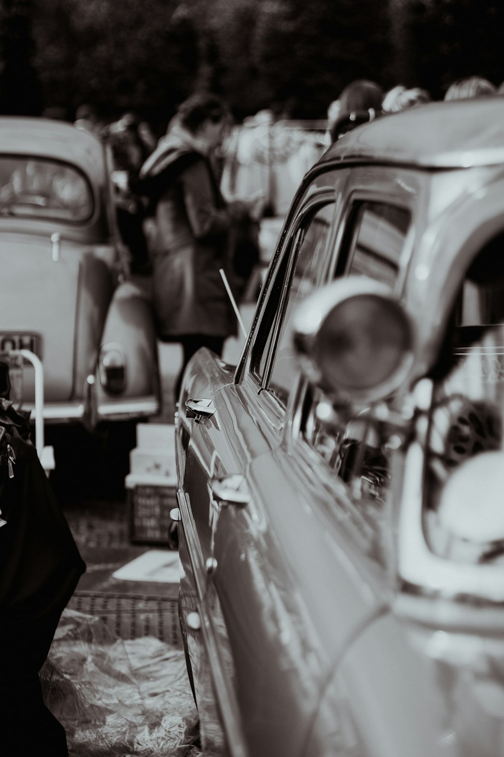 a black and white photo of a woman standing next to a car