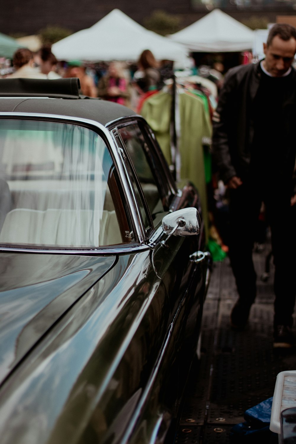 a black car parked next to a crowd of people