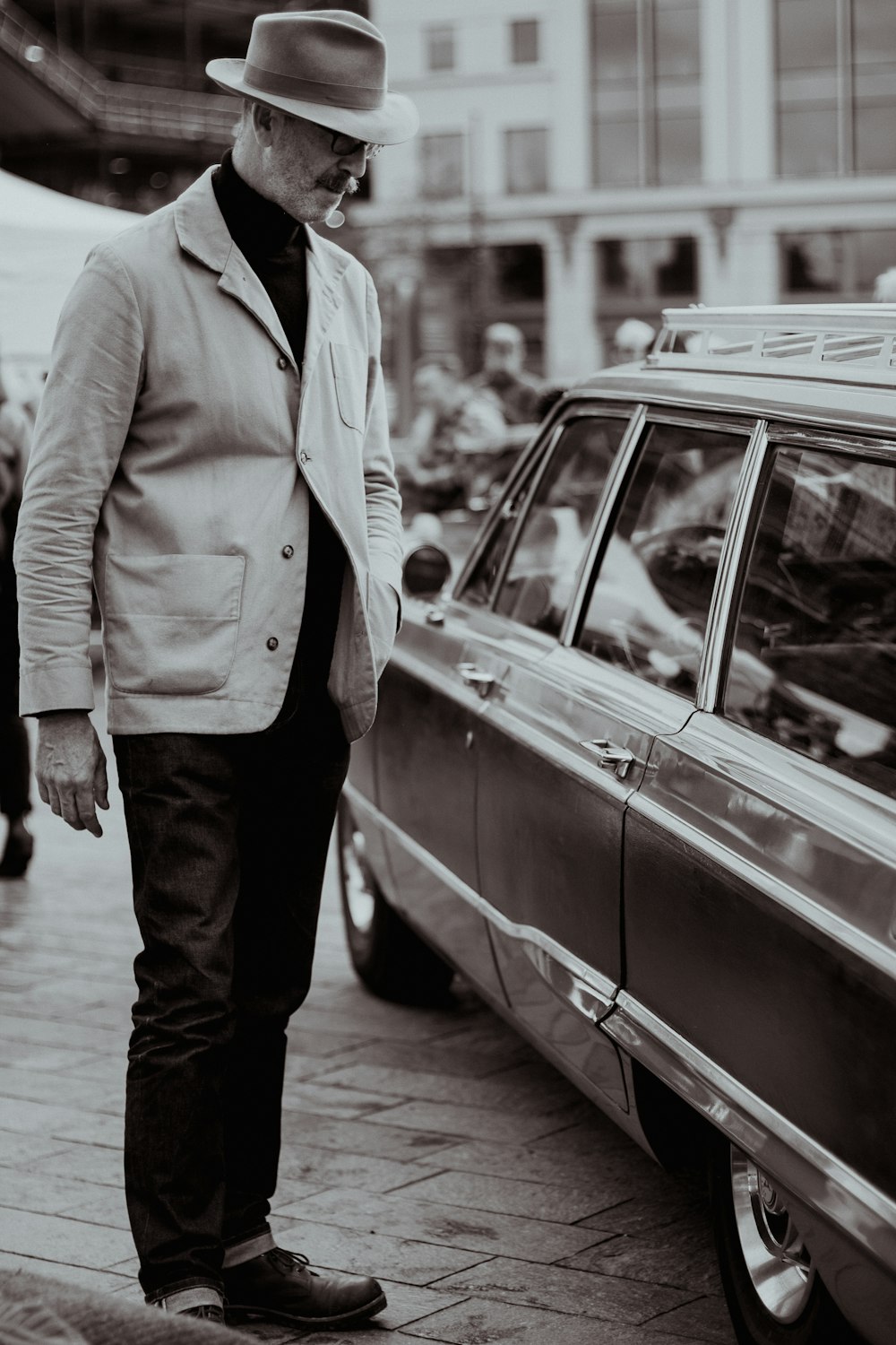 a man standing next to a car on a street