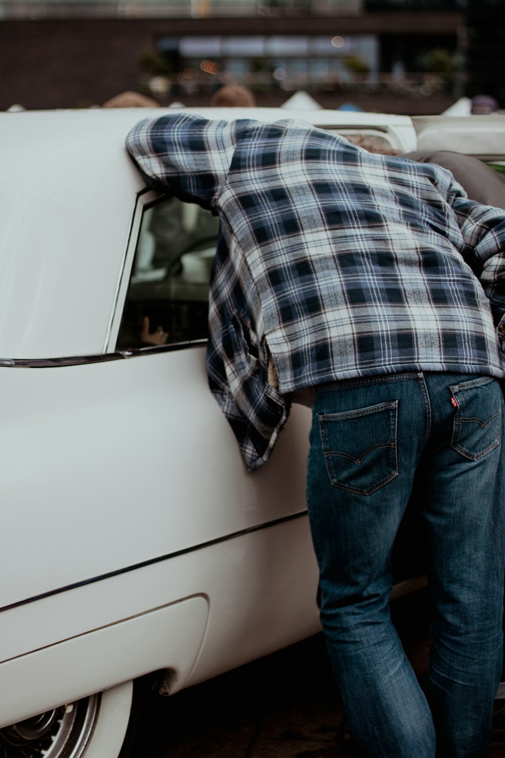 a man leaning on a white car with his hand on the hood