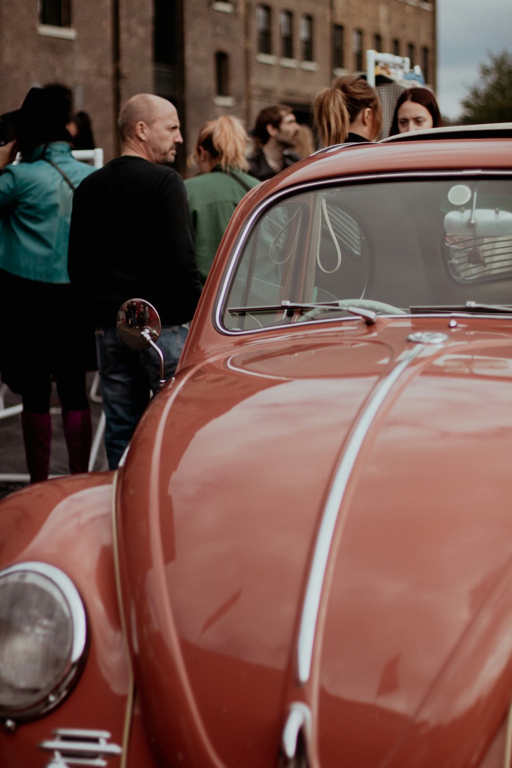 a red car parked in front of a crowd of people