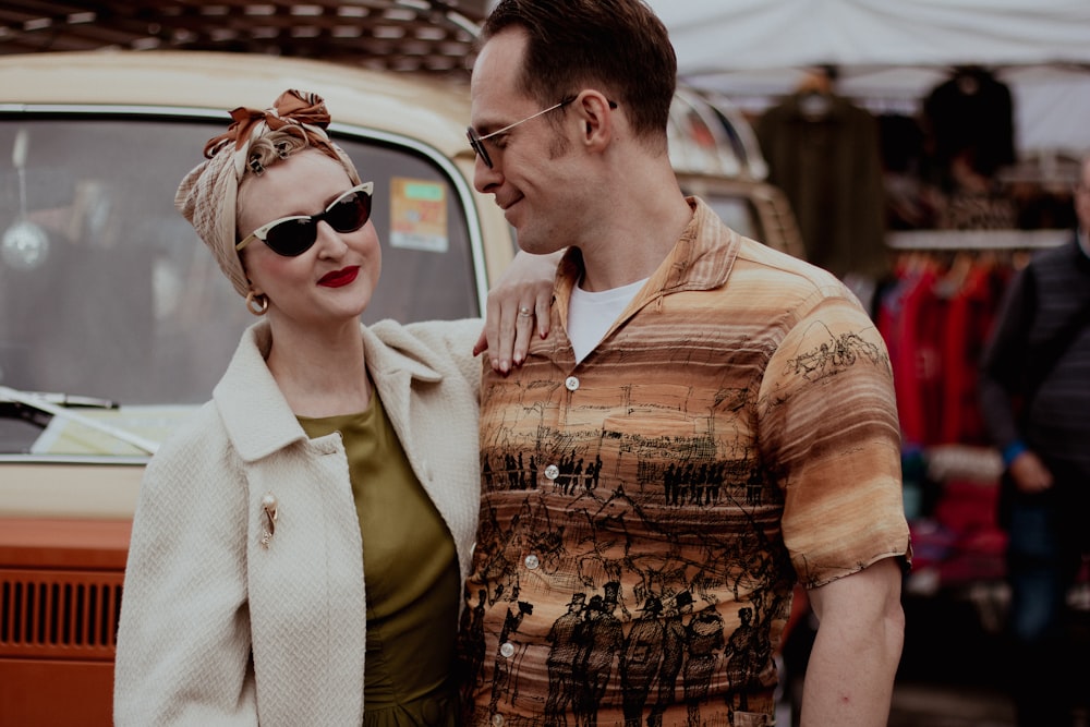 a man and a woman standing next to a car