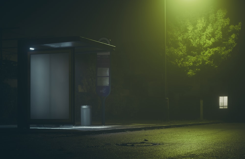 a bus stop sitting on the side of a road at night