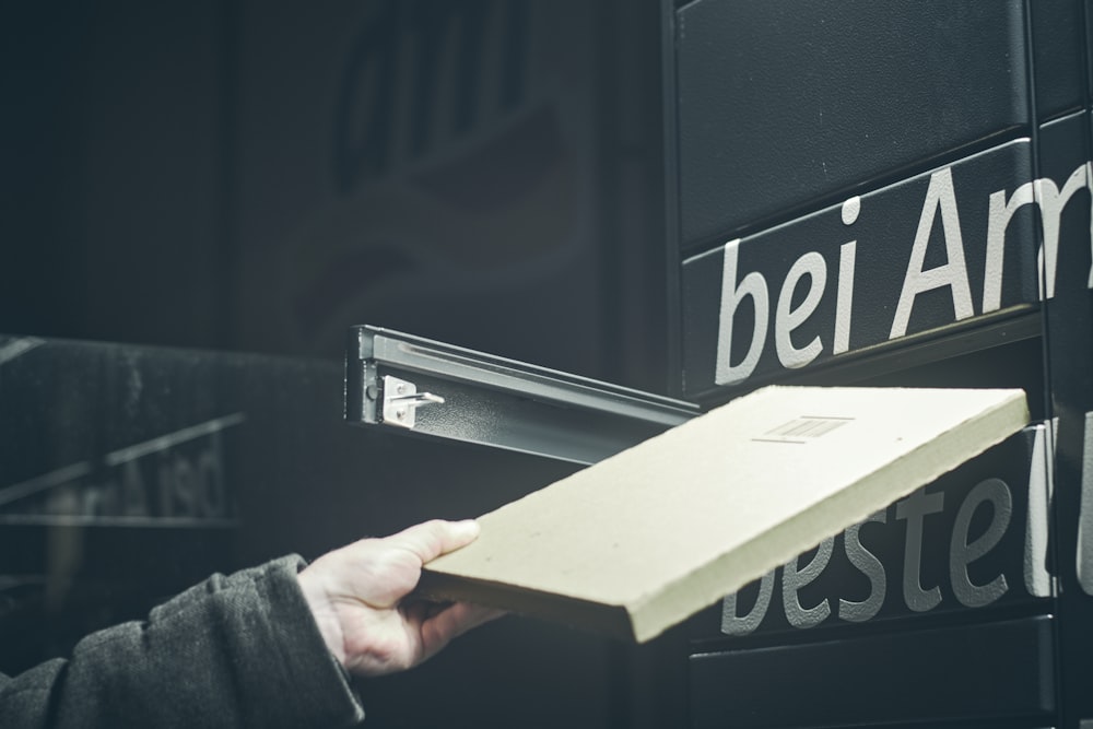 a person holding a box in front of a sign