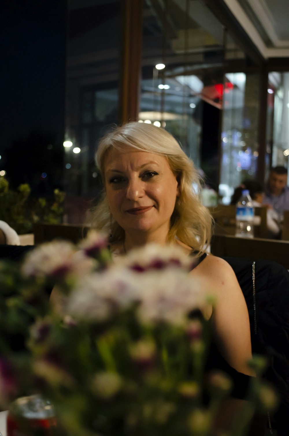 a woman sitting at a table with a vase of flowers