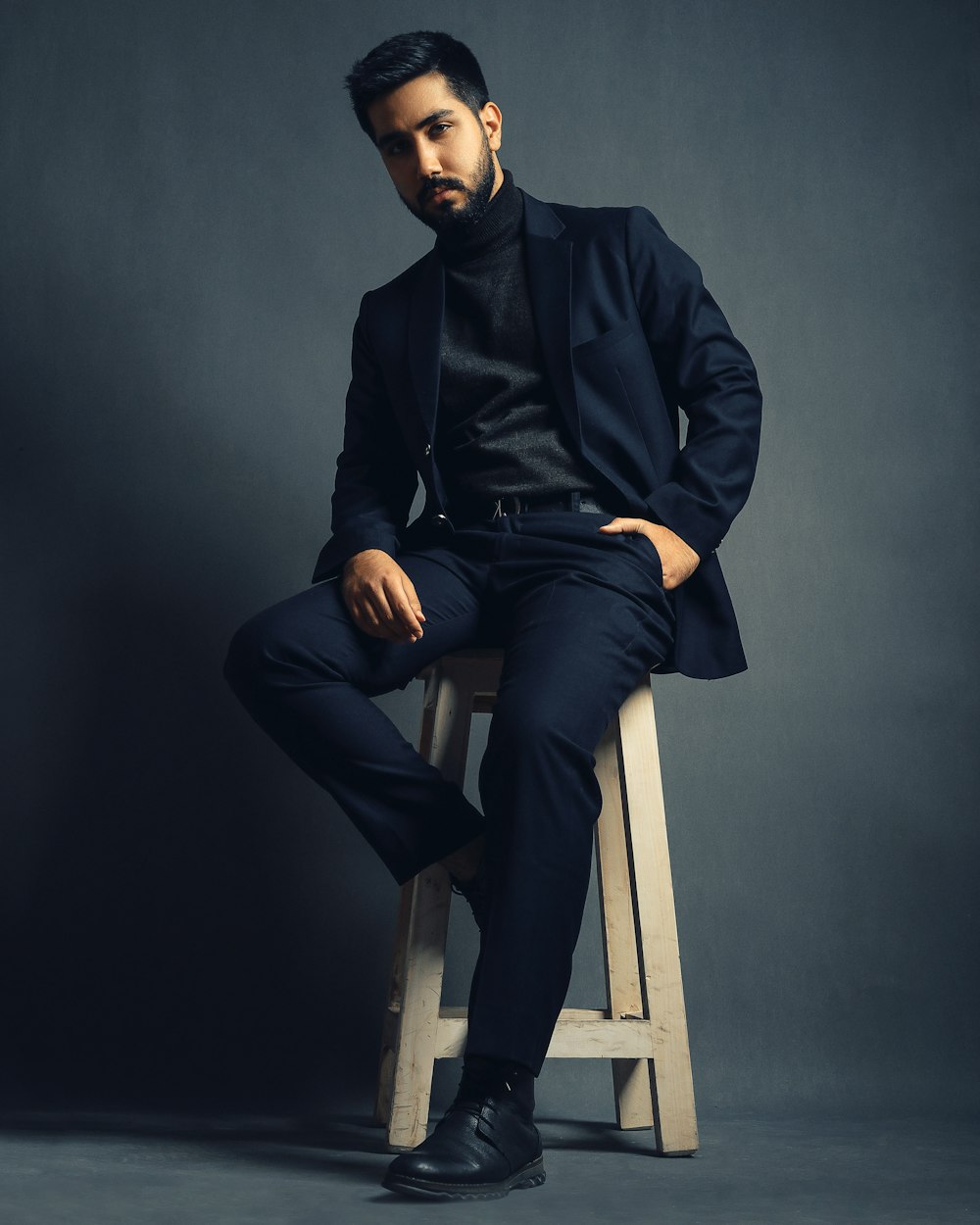 a man sitting on top of a wooden stool