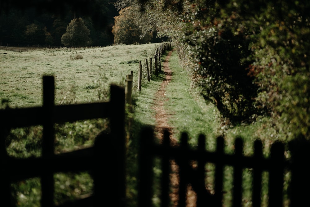 a wooden fence in front of a grassy field