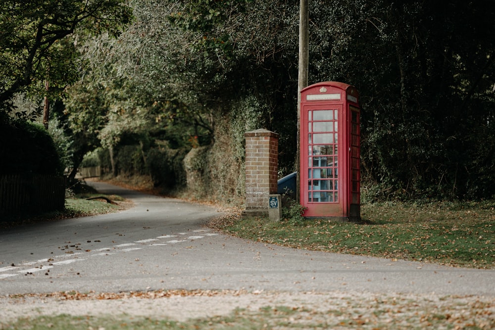 a red phone booth sitting on the side of a road