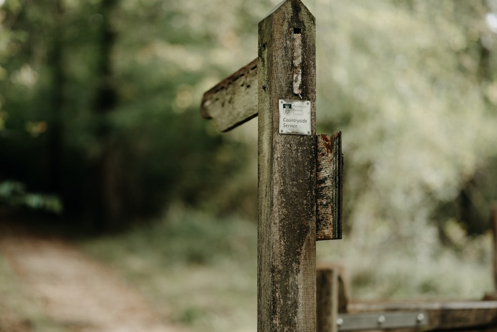a wooden cross with a sign on it in the woods