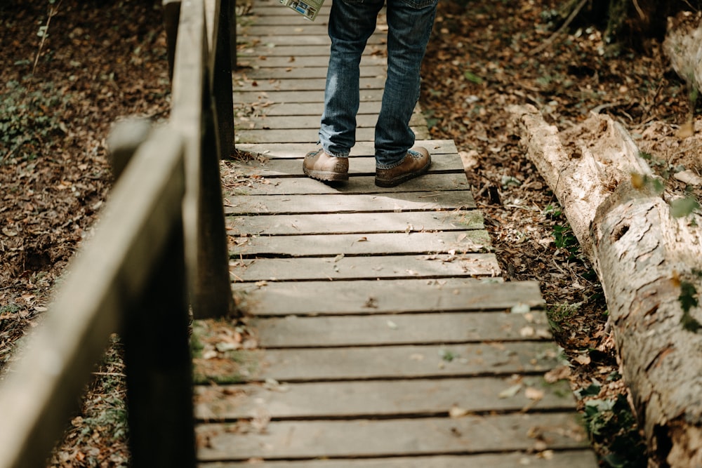 a person walking across a wooden bridge in the woods