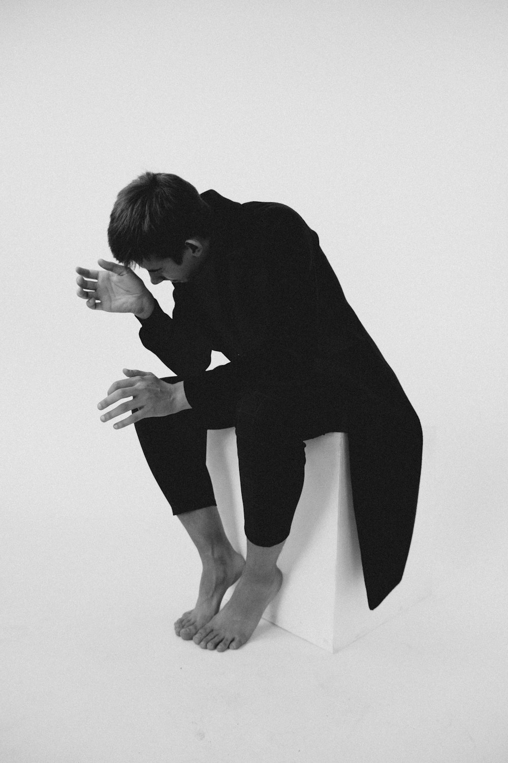 a black and white photo of a man sitting on a toilet