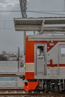 a red and white train traveling down train tracks