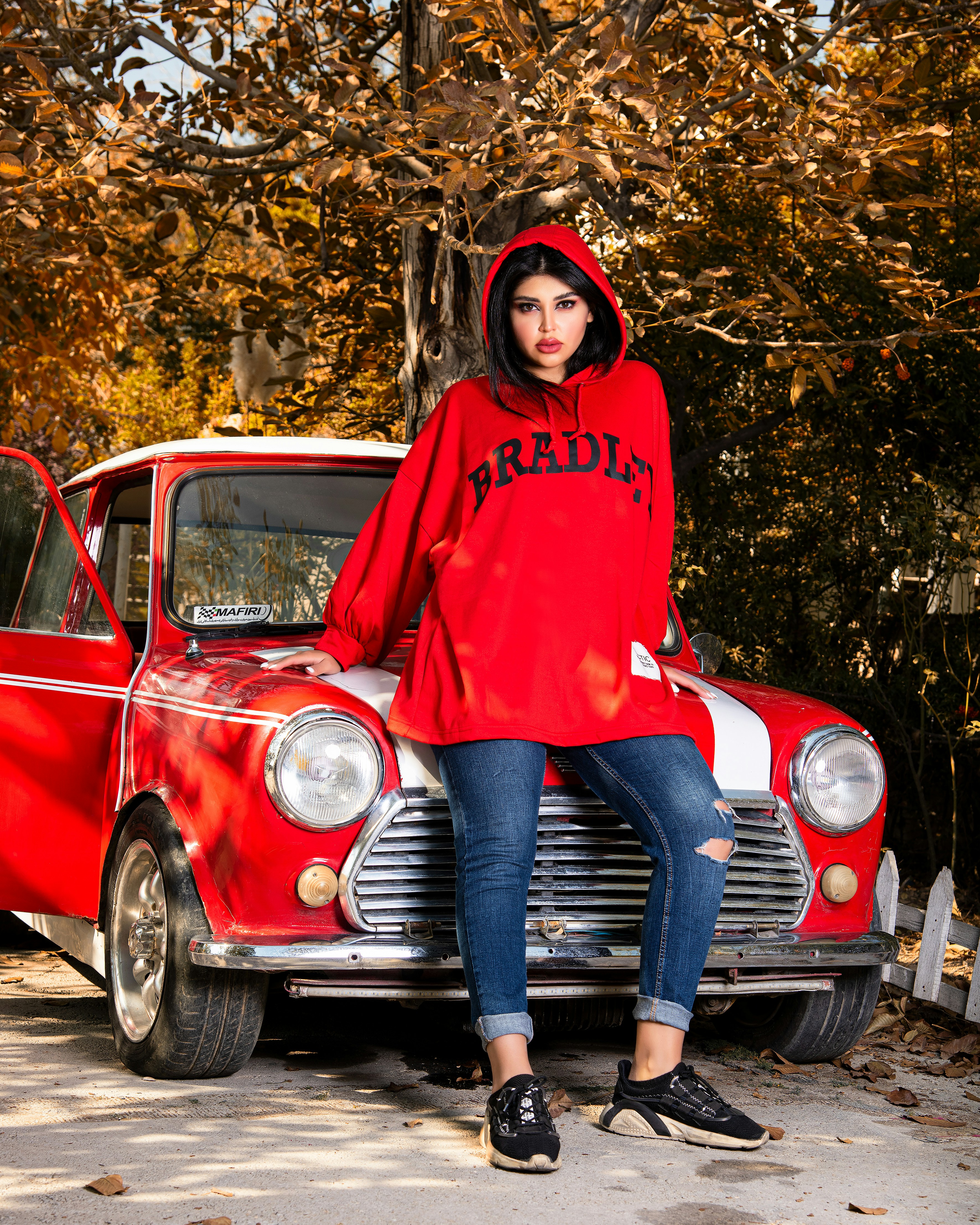 a woman sitting on the hood of a red car