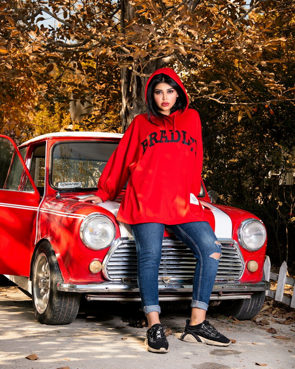a woman sitting on the hood of a red car