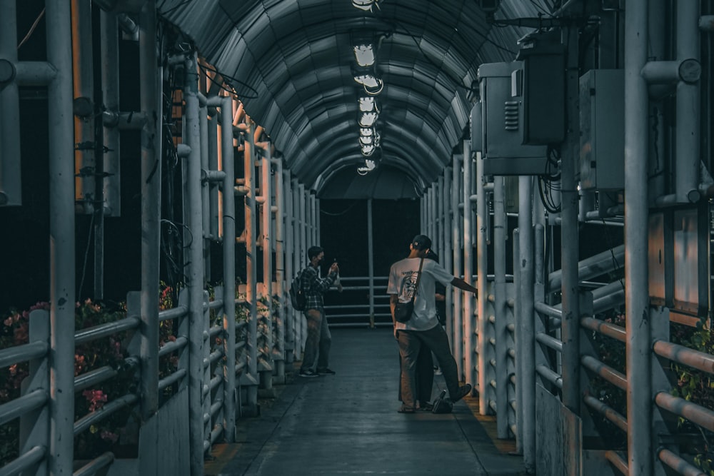 a man is walking down a walkway in a building