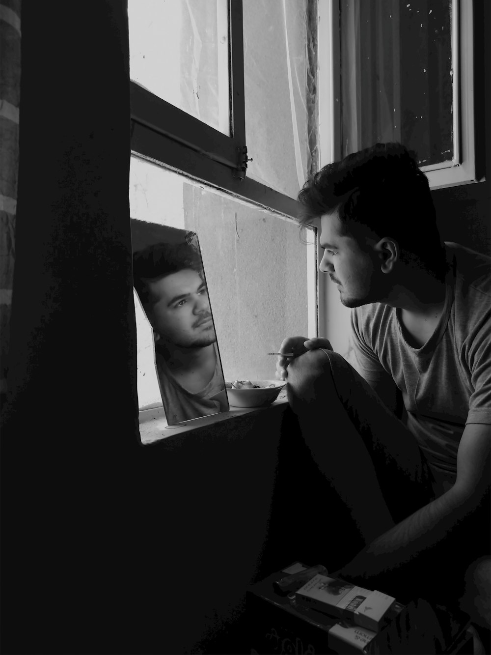 a man sitting on a window sill looking out of a window