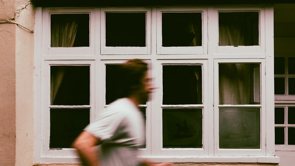 a man walking past a building with a window