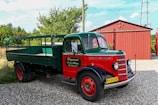 a green and red truck parked next to a red building