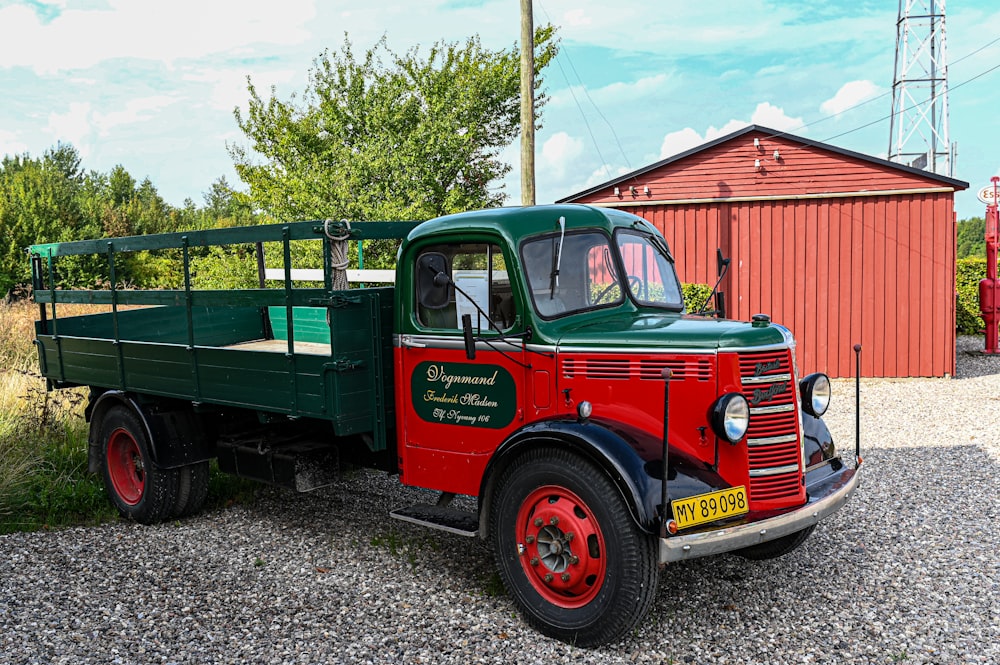 a green and red truck parked next to a red building