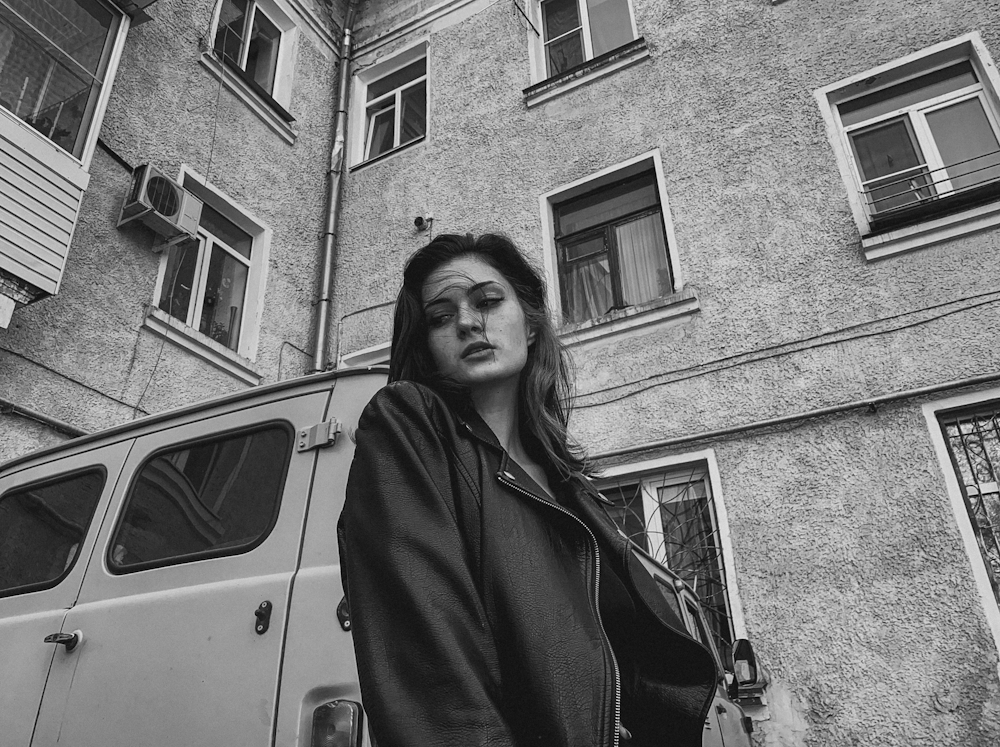 a black and white photo of a woman standing in front of a van