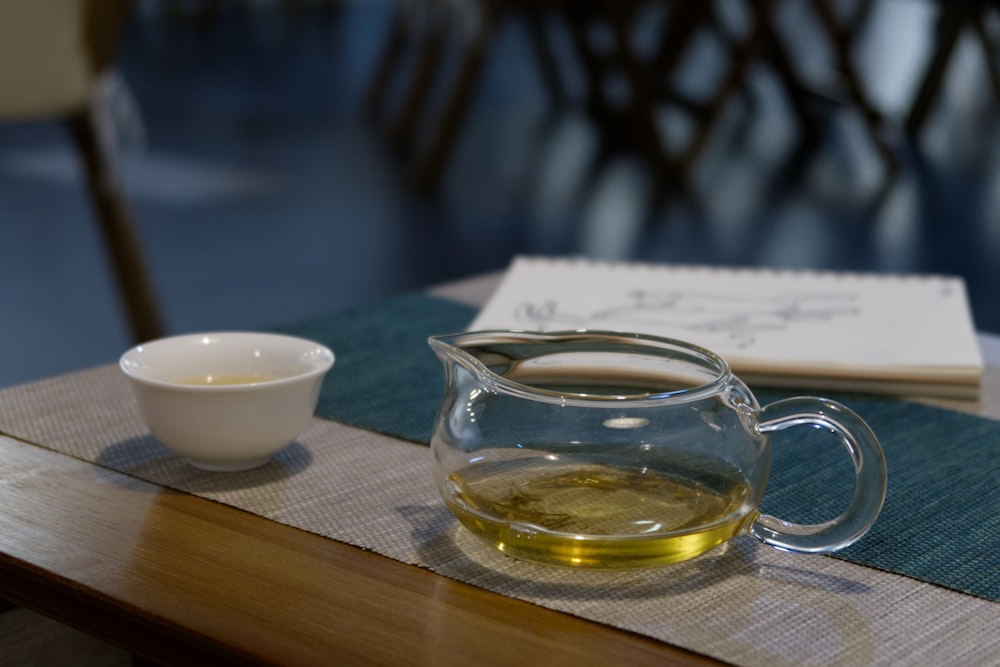 a glass pitcher of liquid next to a bowl of oil