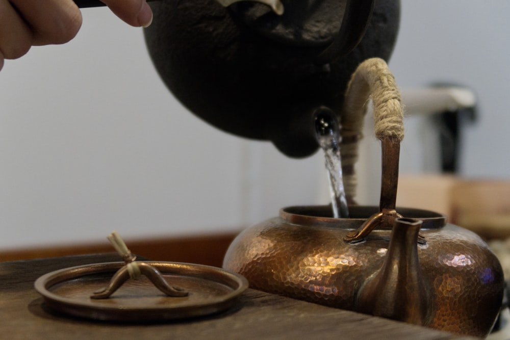 a person is pouring water into a teapot