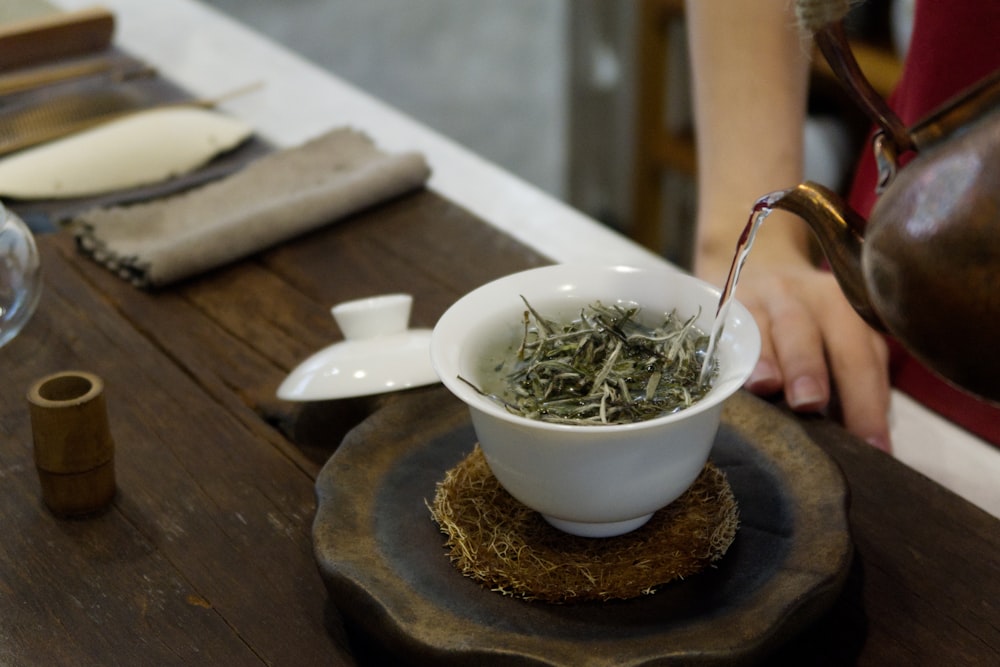 a woman pours tea into a white bowl