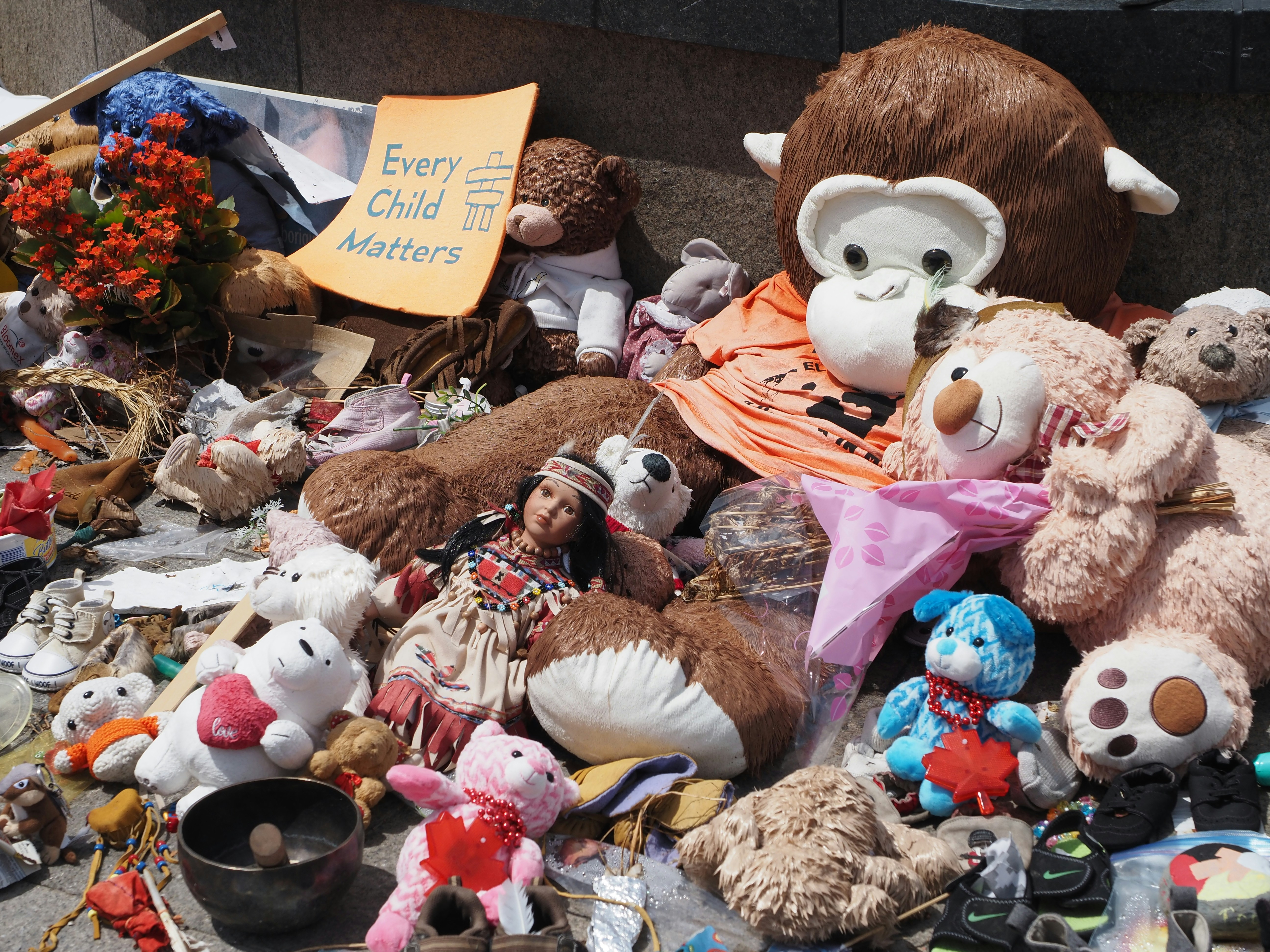 a pile of stuffed animals sitting on top of a sidewalk