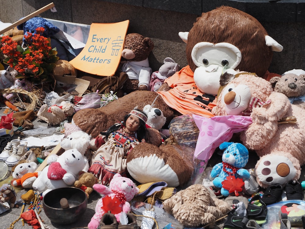 a pile of stuffed animals sitting on top of a sidewalk