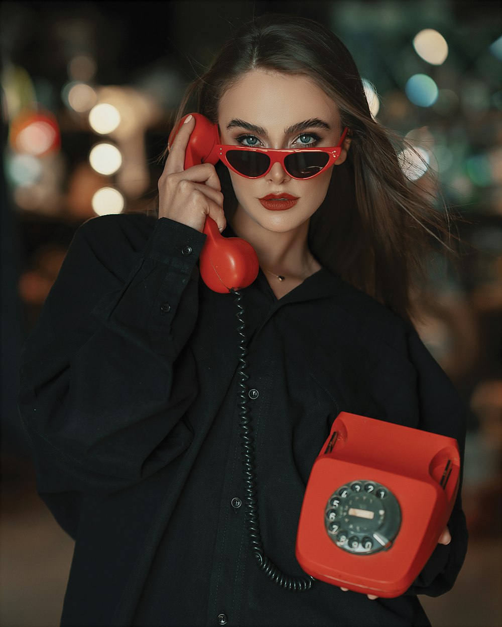 a woman wearing sunglasses and holding a red phone