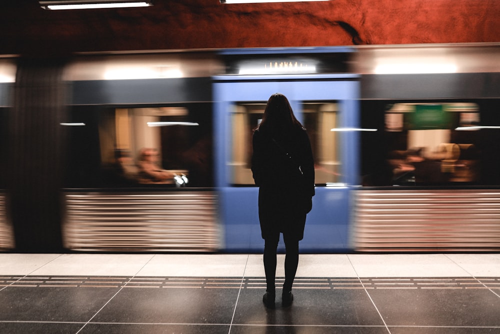 a woman standing in front of a train at a train station