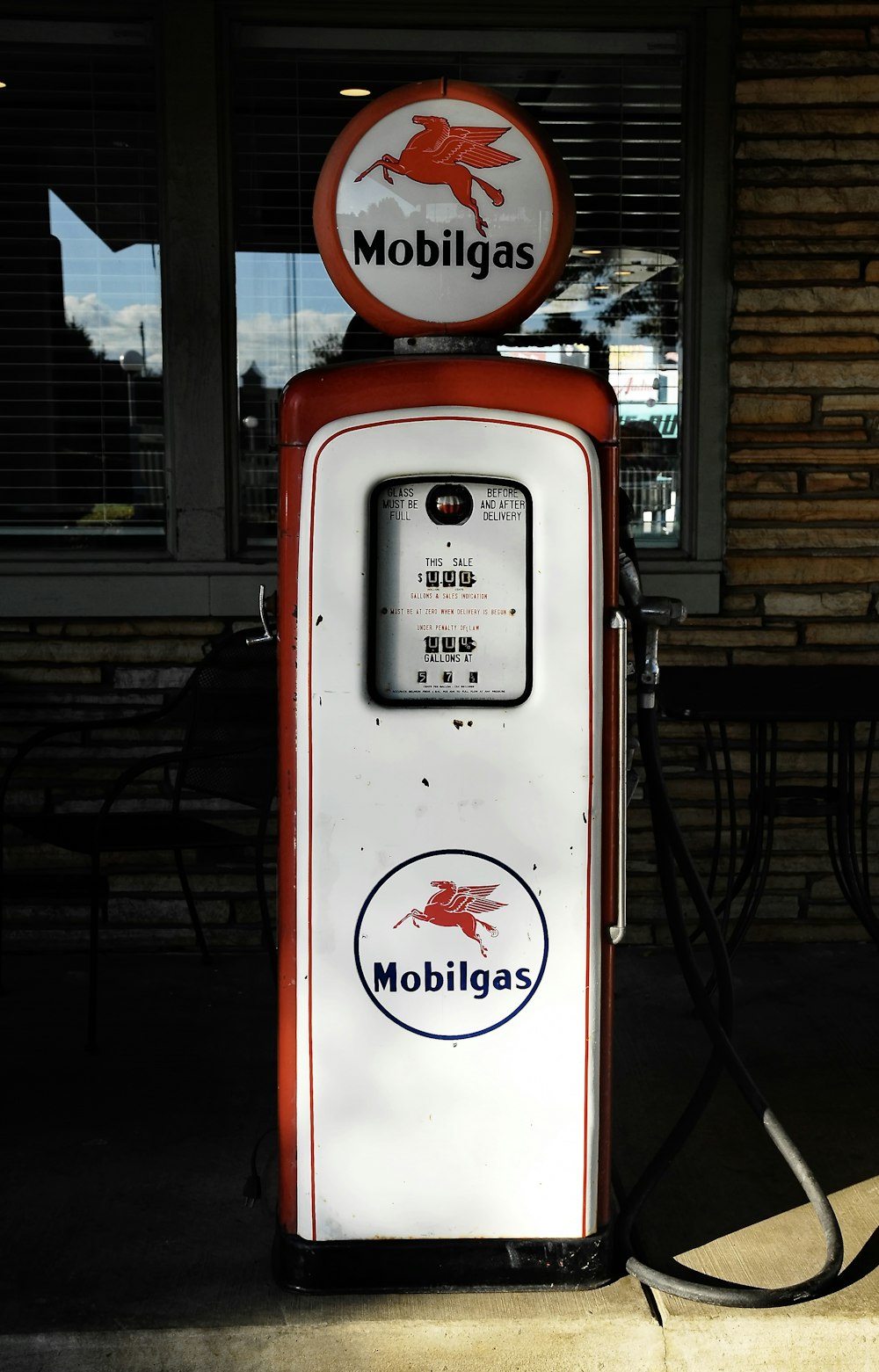 a red and white gas pump sitting in front of a building
