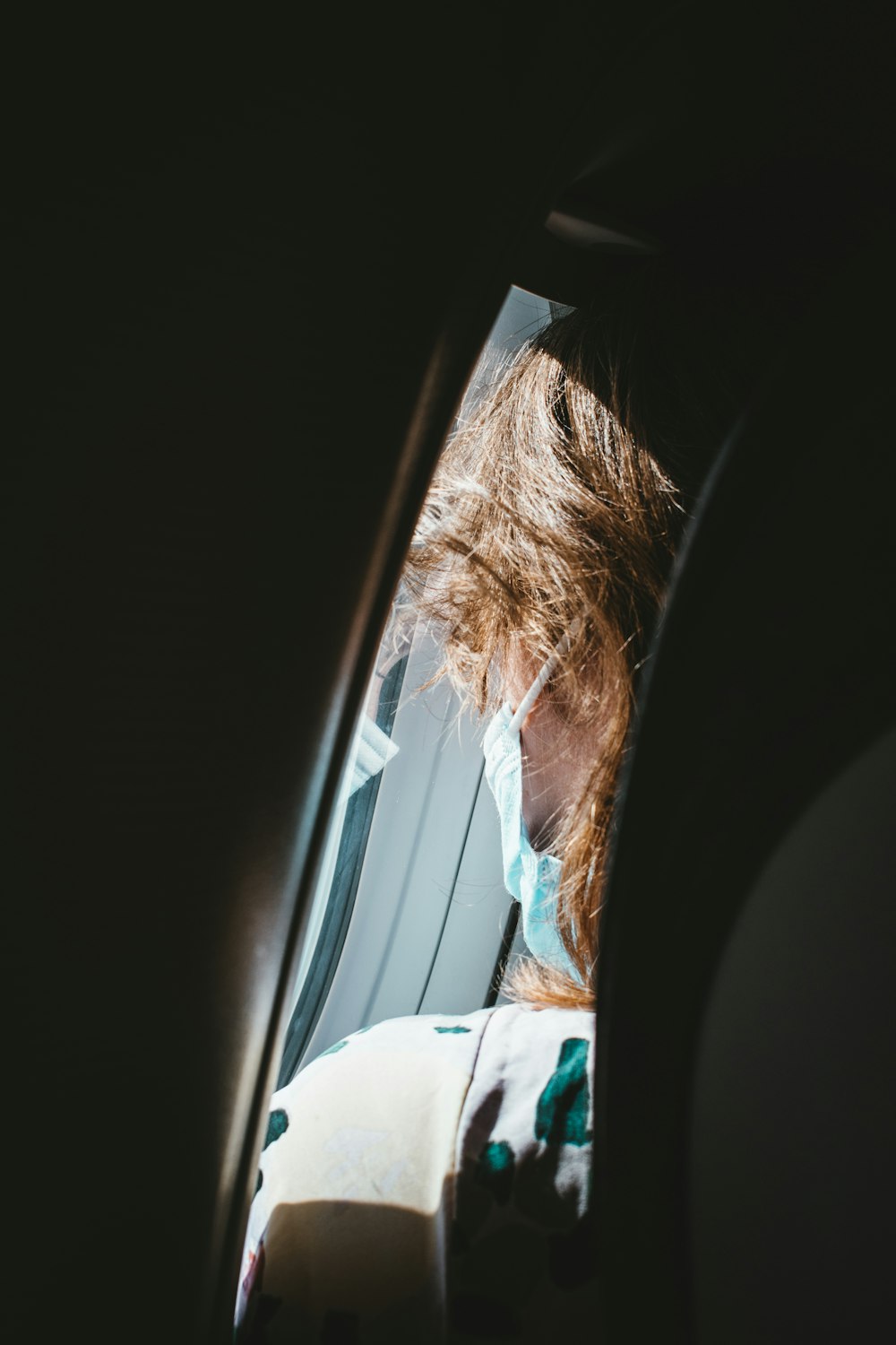 a woman with a face mask looking out of a window