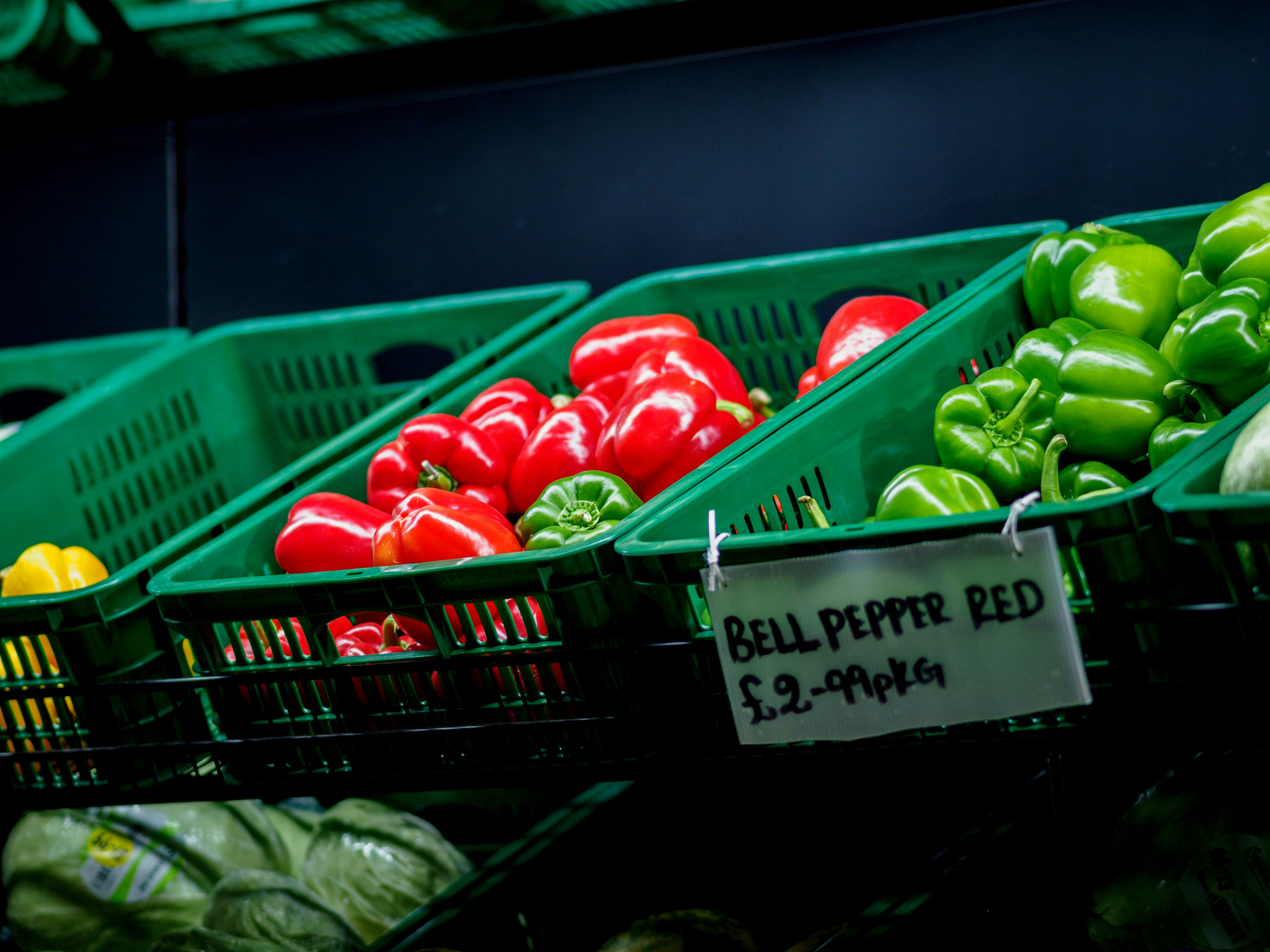 Fresh bright green bell peppers in a wooden crate at a farm market
