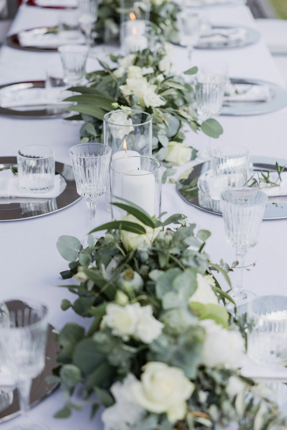 a long table with white flowers and greenery