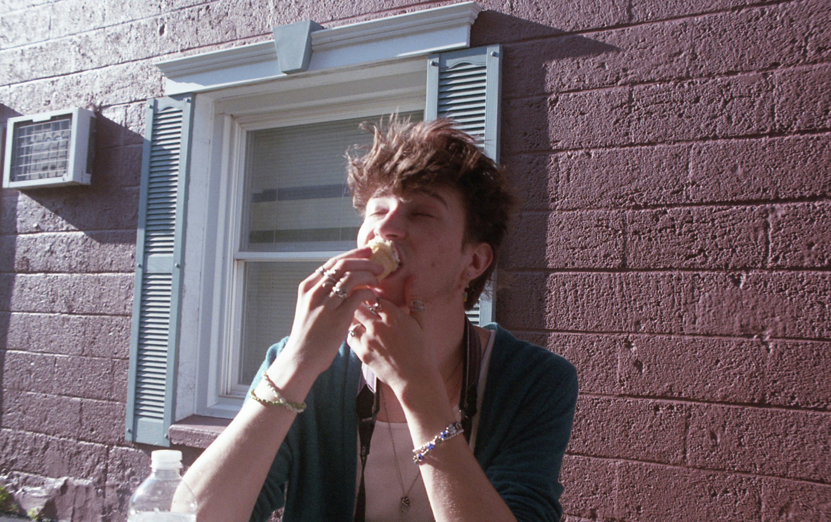 a man eating a doughnut in front of a window