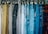 A variety of pants and jeans in different colors and fabrics are hanging on hooks, organized side by side. The pants range from light to dark shades, including corduroy and denim materials.