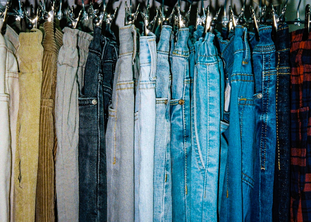 um rack de jeans de cores diferentes pendurados em ganchos